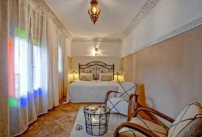 a bedroom with a bed and chairs in a room at Riad Basim in Marrakech