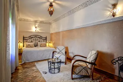 a bedroom with a bed and two chairs in it at Riad Basim in Marrakech