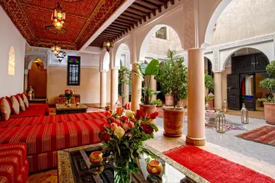 a living room with a red couch and a table with flowers at Riad Basim in Marrakech