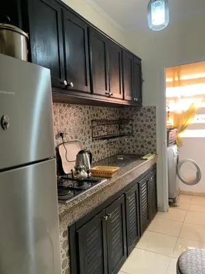 a kitchen with black cabinets and a stainless steel refrigerator at Appartement zen in Marrakech
