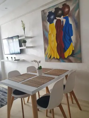 a dining room table and chairs with a painting on the wall at Apparemment yasmina in Marrakech