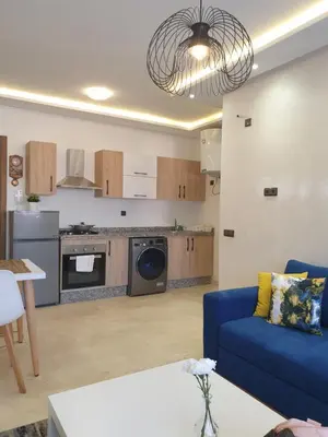a living room with a blue couch and a kitchen at Apparemment yasmina in Marrakech