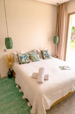 a bedroom with a white bed with pillows and a window at Villa des sœurs bradaa in Marrakech