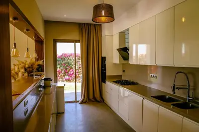 a kitchen with white cabinets and a large window at Villa des sœurs bradaa in Marrakech
