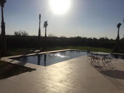 a pool with a table and chairs and palm trees at Villa Jamila -Villa de luxe a Marrakech in Marrakech