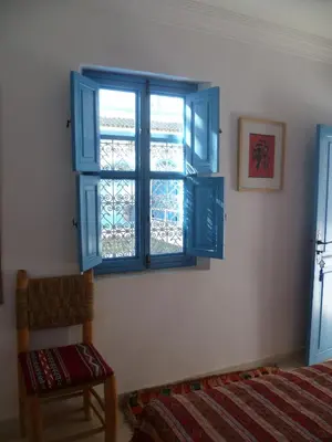 a bedroom with a blue window and a chair at Dar Daoud in Marrakech
