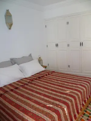a bedroom with a bed with a striped blanket on it at Dar Daoud in Marrakech