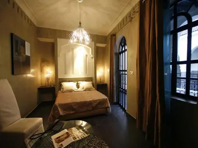 a bedroom with a bed and a couch and a chandelier at Riad Carllian in Marrakech