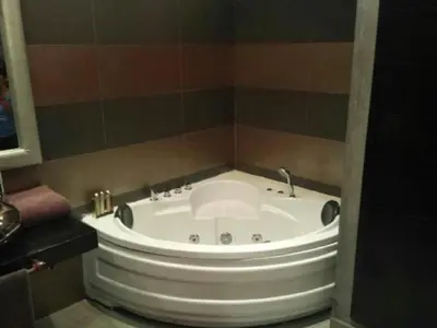 a large white tub in a bathroom with a tiled wall at Riad Carllian in Marrakech