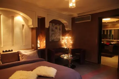 a bedroom with a bed and a chair and a table at Riad Carllian in Marrakech