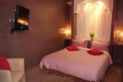 a bedroom with a bed and a tv on a wall at Riad Carllian in Marrakech