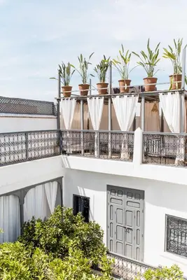a white building with potted plants on the balcony at RIAD MAGIE Boutique Hotel in Marrakech
