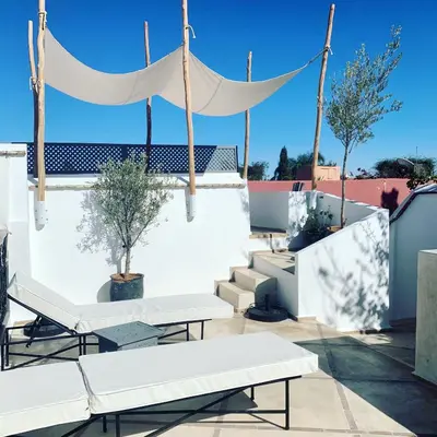 a rooftop patio with white benches and a canopy at RIAD MAGIE Boutique Hotel in Marrakech