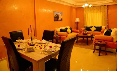 a dining room with a table and a living room at Hôtel La Citta Rossa in Marrakech