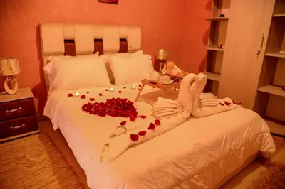 a bedroom with a white bed with red roses on it at Hôtel La Citta Rossa in Marrakech