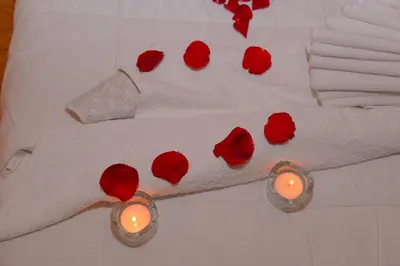 a bed with red roses and two candles on it at Hôtel La Citta Rossa in Marrakech