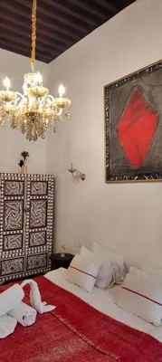 a bedroom with a large bed with a chandelier at Riad Siena II in Marrakech