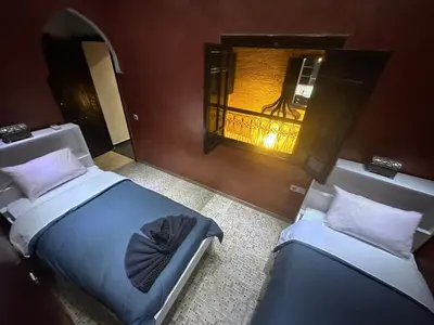 two twin beds in a room with a window at Riad luna in Marrakech