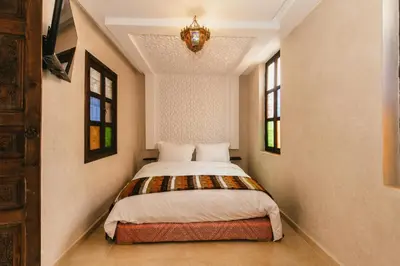 a bedroom with a bed in a room with a chandelier at L'Emeraude de la Médina in Marrakech
