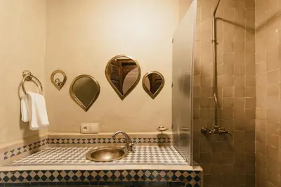 a bathroom with a sink and a shower with mirrors at L'Emeraude de la Médina in Marrakech