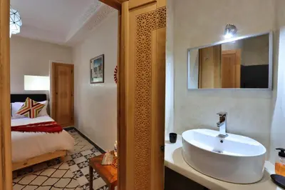 a bathroom with a white sink and a bed at Riad Banatti in Marrakech