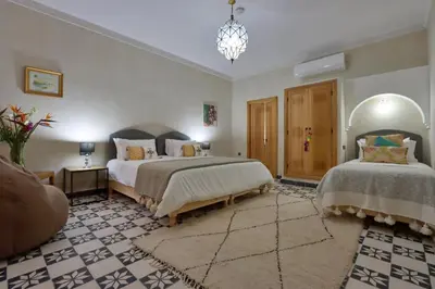 a large bedroom with two beds and a chandelier at Riad Banatti in Marrakech
