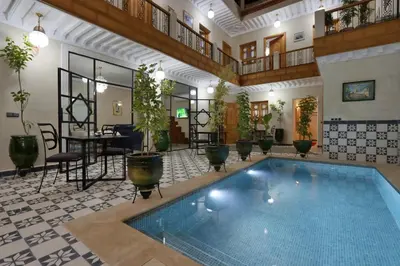 a large pool in a room with a table and chairs at Riad Banatti in Marrakech