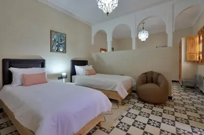 a hotel room with two beds and a chair at Riad Banatti in Marrakech
