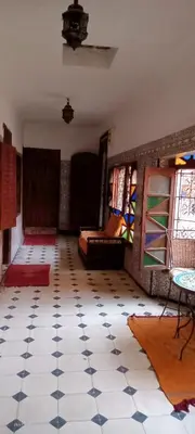 a room with a tiled floor with a couch and windows at Riad Dar Zaida in Marrakech