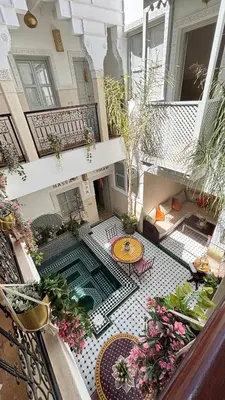 an indoor courtyard with a table and flowers on a balcony at Riad Magnolia&SPA in Marrakech