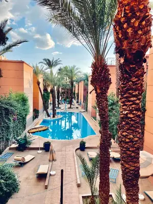 an overhead view of a resort pool with palm trees at Très Beau Riad à Marrakech avec piscines in Marrakech