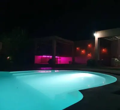 a swimming pool lit up at night with purple lights at RIAD - Jnan Bnati - Pool in Marrakech