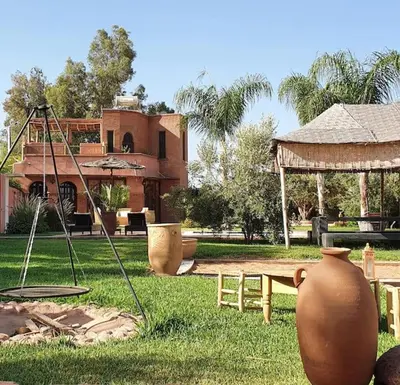 a yard with vases and a swing and a house at RIAD - Jnan Bnati - Pool in Marrakech