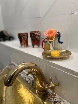 a bathroom sink with a gold faucet and a plate with a flower at Riad Malfa in Marrakech