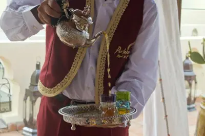 a man is holding a tray with a drink at Perlekech Riad & Spa in Marrakech