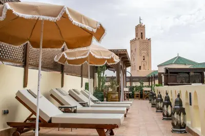 a row of lounge chairs with an umbrella on a patio at Perlekech Riad & Spa in Marrakech