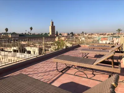 a patio with benches and tables on a roof at Riad Home Zemrane in Marrakech