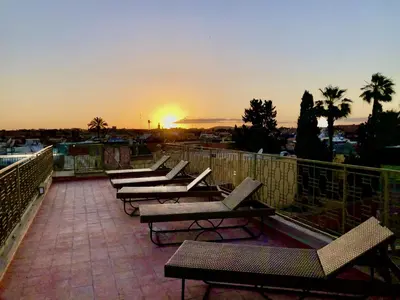 a row of benches on a balcony with the sunset at Riad Home Zemrane in Marrakech