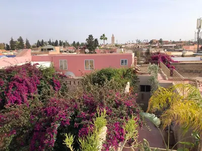 a pink house with purple flowers and plants at Riad Home Zemrane in Marrakech