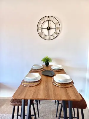 a wooden table with plates and a clock on the wall at Magnifique appartement Résidence DOMAINE DE NORIA in Marrakech