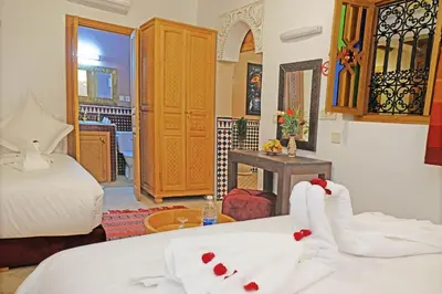 a bedroom with two beds with white sheets and red bows at Riad ZANOUBA in Marrakech