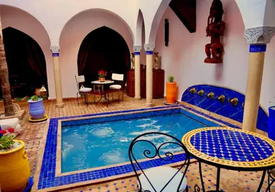 a swimming pool with chairs and a table in a room at Riad Rêve d Antan , Real Dream in Marrakech
