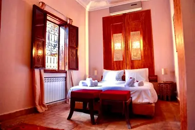 a bedroom with a white bed and two windows at Riad Rêve d Antan , Real Dream in Marrakech