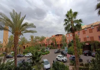 a parking lot with parked cars and palm trees at RIAD ZAKARYA in Marrakech