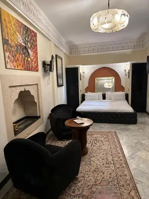 a hotel room with a bed and a couch and chairs at Riad Palais Didier Six in Marrakech