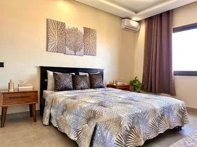a bedroom with a king sized bed and two paintings on the wall at Moderne, lumineux & spacieux avec balcon -Central -Wifi-Smart TV-Clim in Marrakech