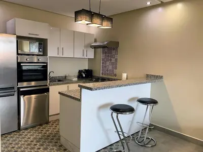 a kitchen with a counter and two stools in it at Moderne, lumineux & spacieux avec balcon -Central -Wifi-Smart TV-Clim in Marrakech