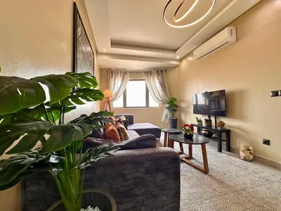 a living room with a blue couch and a window at Moderne, lumineux & spacieux avec balcon -Central -Wifi-Smart TV-Clim in Marrakech