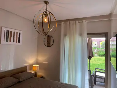 a bedroom with a bed and a chandelier at Appartement de Luxe -Prestigia Marrakech Golf City in Marrakech