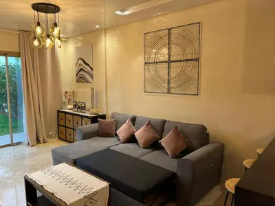 a living room with a couch and a table at Appartement de Luxe -Prestigia Marrakech Golf City in Marrakech